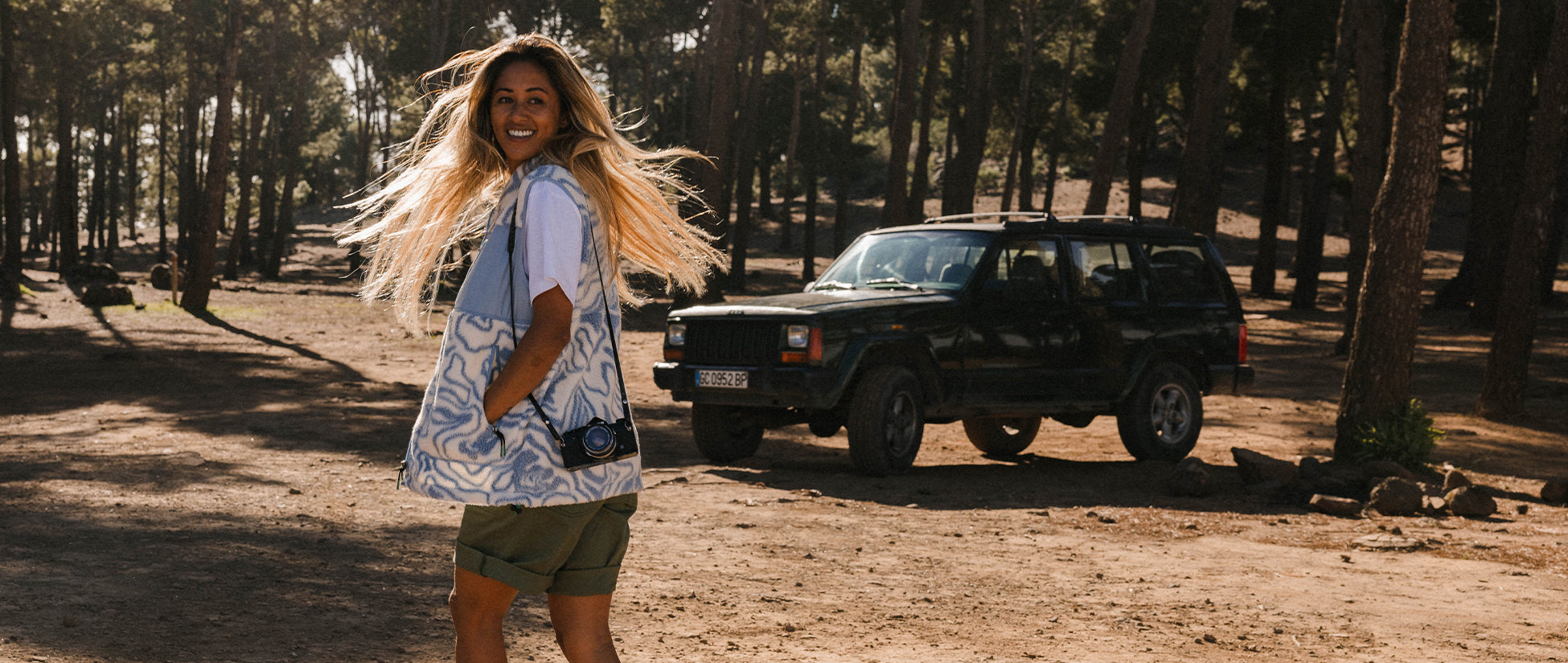 A woman walking towards a jeep, turning to smile