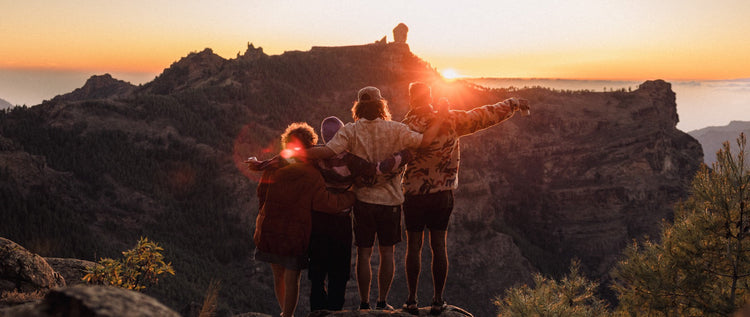 Four friends watch the sun set over the mountains