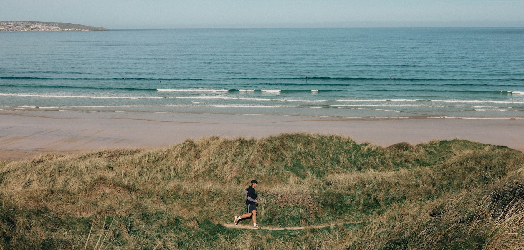 A man running along a coastal path with the sea in the background