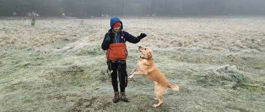 A woman stands with her dog on a frosty morning.