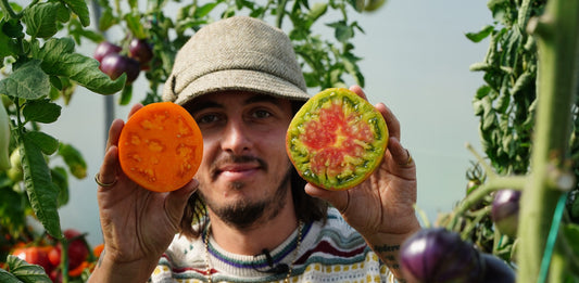 A man holding up two tomato halves to the camera