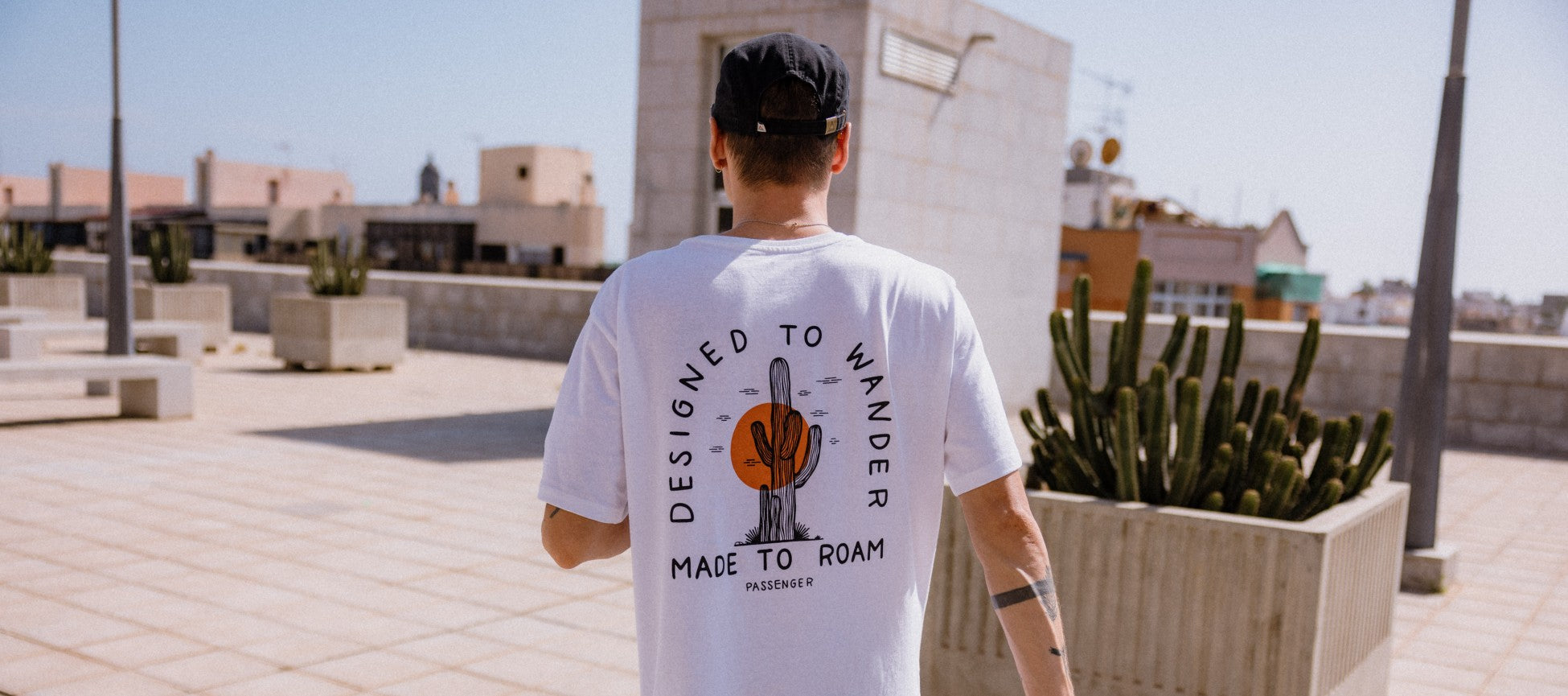 A man with his back to the camera walking along a rooftop